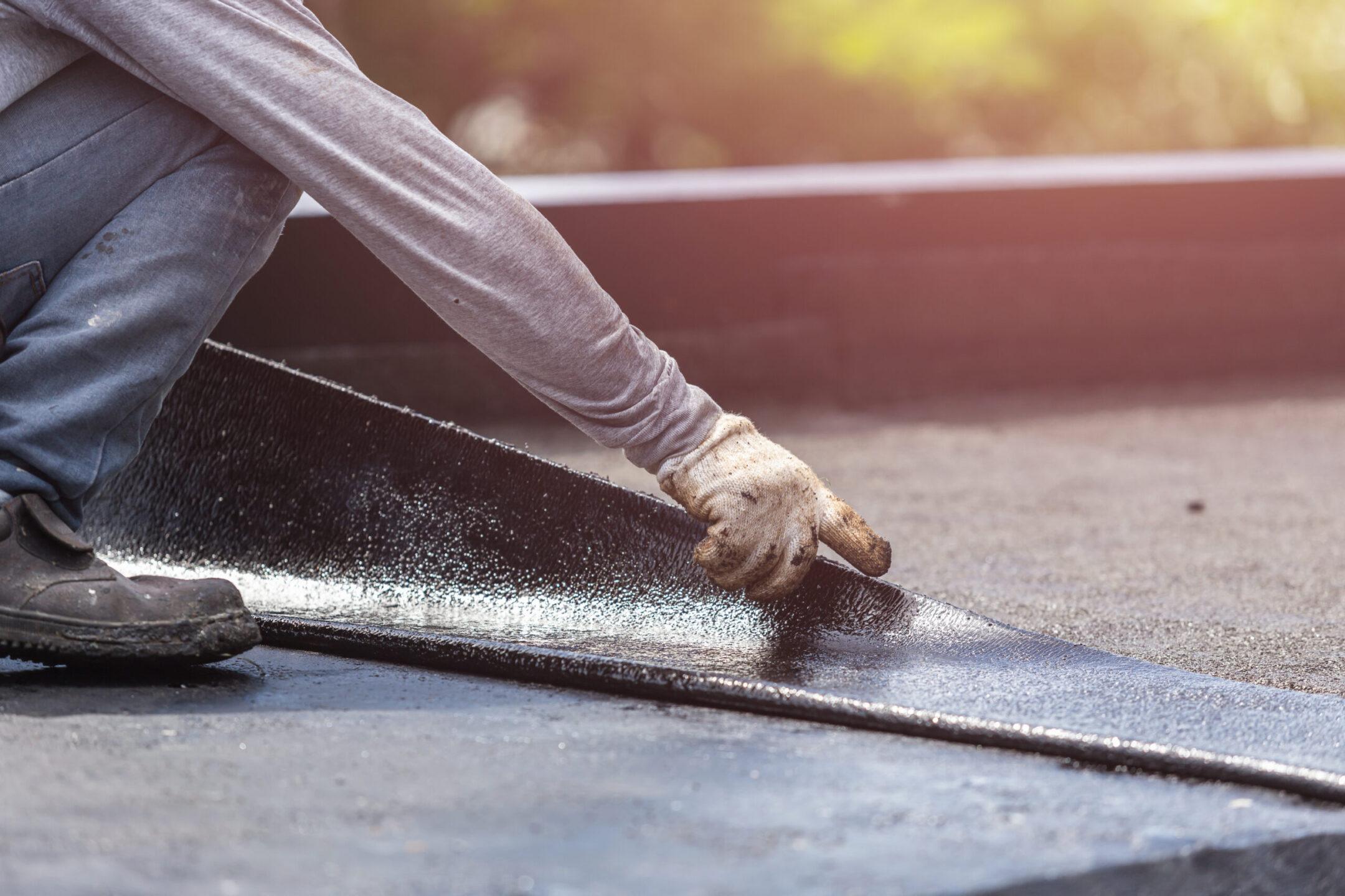 worker installing tar foil on the rooftop of building.