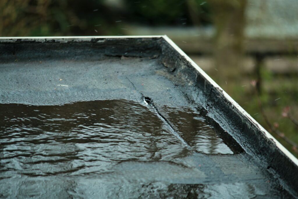 Light rain on a black flat roof after hail