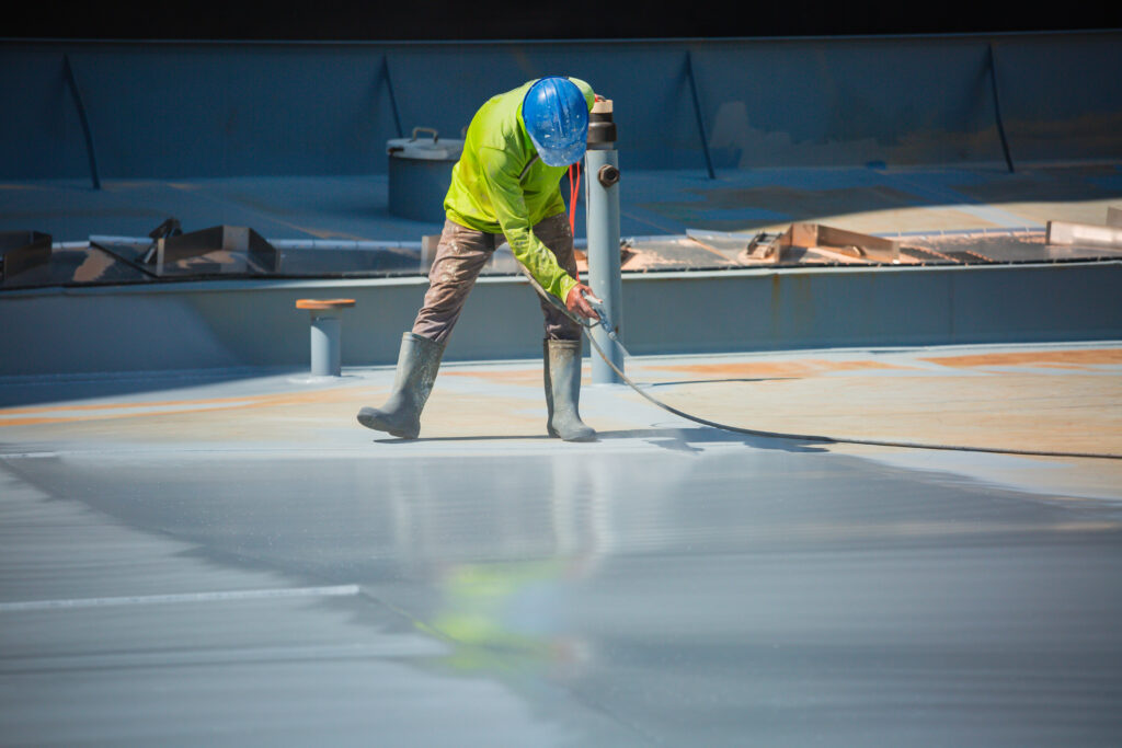 A male worker holding an industrial spray gun used for roof plate tank surface on steel industrial painting and coating.