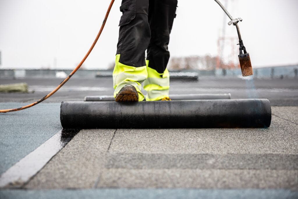 professional roofer applying tar with blowtorch