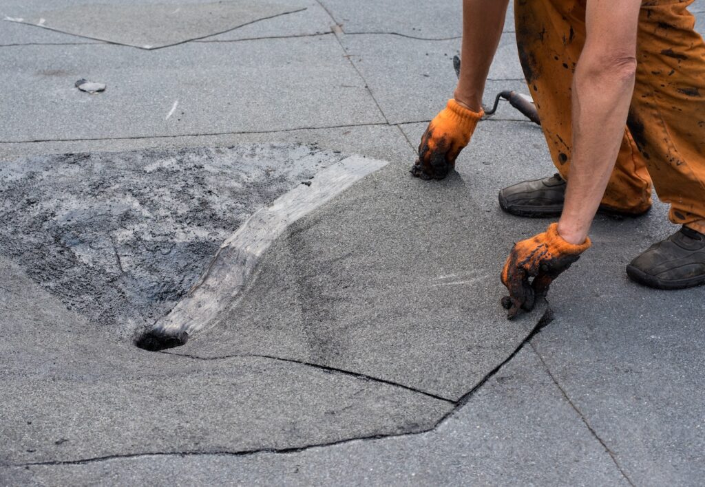 Roofer doing repair  roof drain. Flat roof installation. Heating and melting bitumen roofing felt. Flat roof repairing with roofing felt. Professional master , making waterproofing.