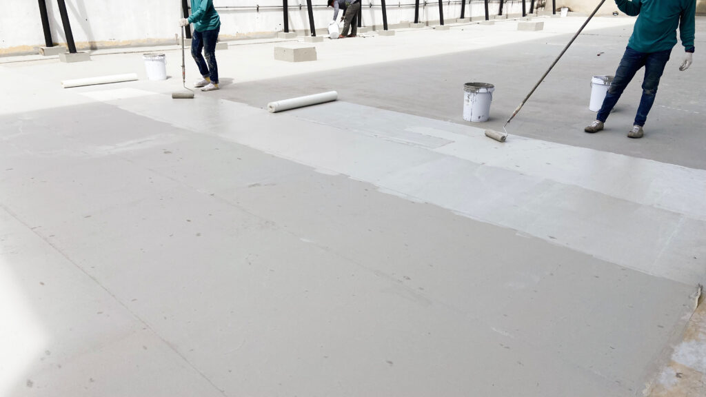 Repairman fixing a leaking roof or deck by applying waterproofing solution
